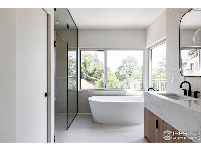 The en suite primary bathroom impresses with treetop views, a walk-in steam shower for two, a freestanding soaking tub, a water closet and a double vanity.