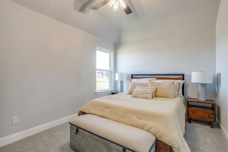 Carpeted bedroom with lofted ceiling and ceiling fan