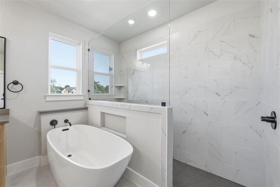 Bathroom with a marble finish shower, plenty of natural light, a freestanding tub, and recessed lighting