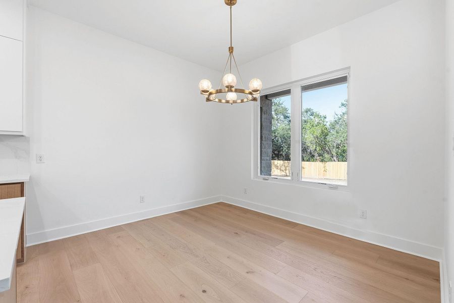 Warm hardwood flooring and a classic light fixture define this inviting dining area.