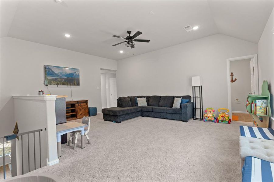 Upstairs carpeted living room/playroom featuring vaulted ceiling, recessed lighting, and a ceiling fan