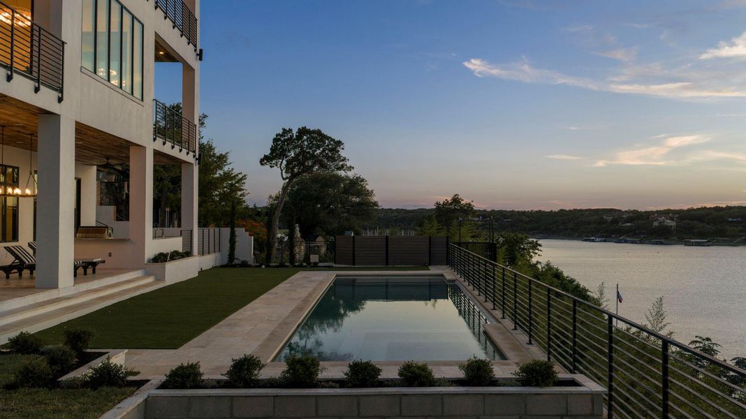 An exquisite outdoor pool offers tranquil waters, set against a magnificent lake view and verdant landscaping. An exquisite outdoor pool offers tranquil waters, set against a magnificent lake view and verdant landscaping.