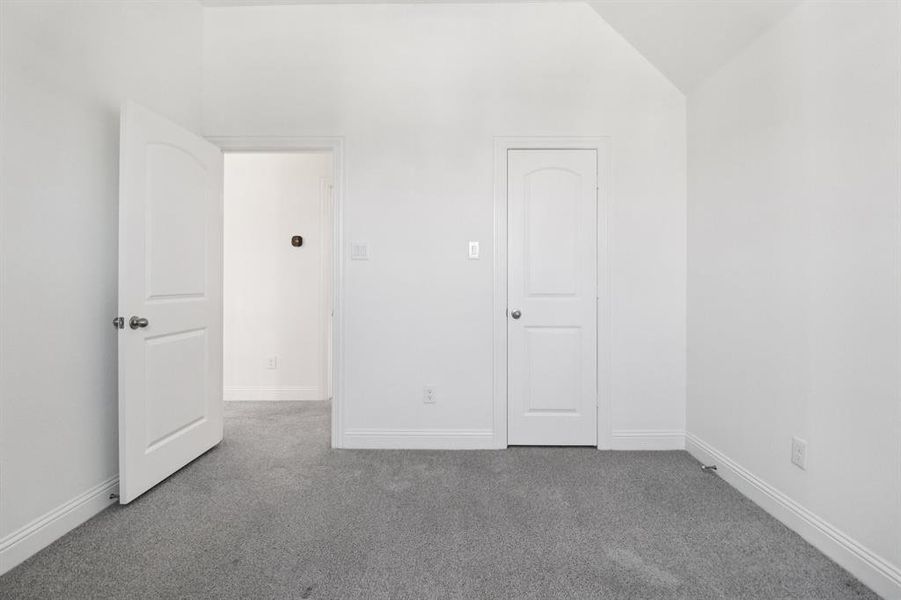 Unfurnished bedroom with carpet flooring and lofted ceiling Unfurnished bedroom with carpet flooring and lofted ceiling