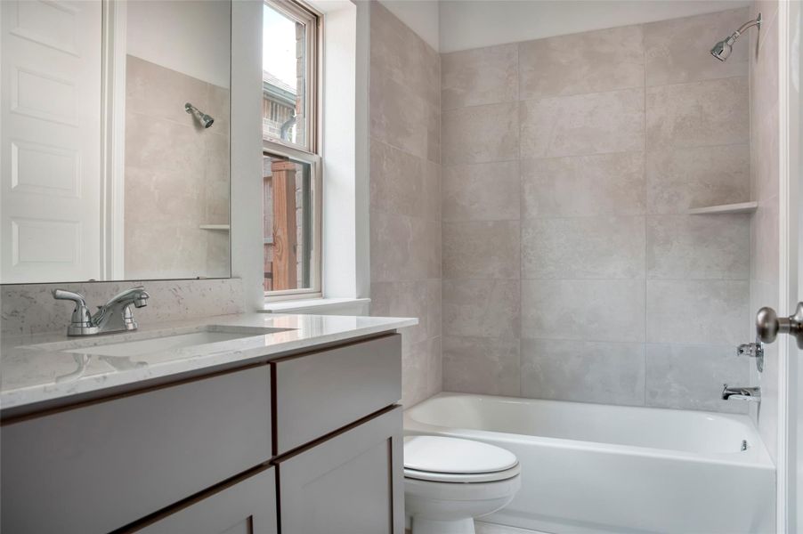 This photo features a modern bathroom with a sleek, tiled bathtub and shower combination. It has a large window allowing natural light, a stylish vanity with a marble countertop, and contemporary fixtures. The neutral tones create a clean, spacious feel. This photo features a modern bathroom with a sleek, tiled bathtub and shower combination. It has a large window allowing natural light, a stylish vanity with a marble countertop, and contemporary fixtures. The neutral tones create a clean, spacious feel.