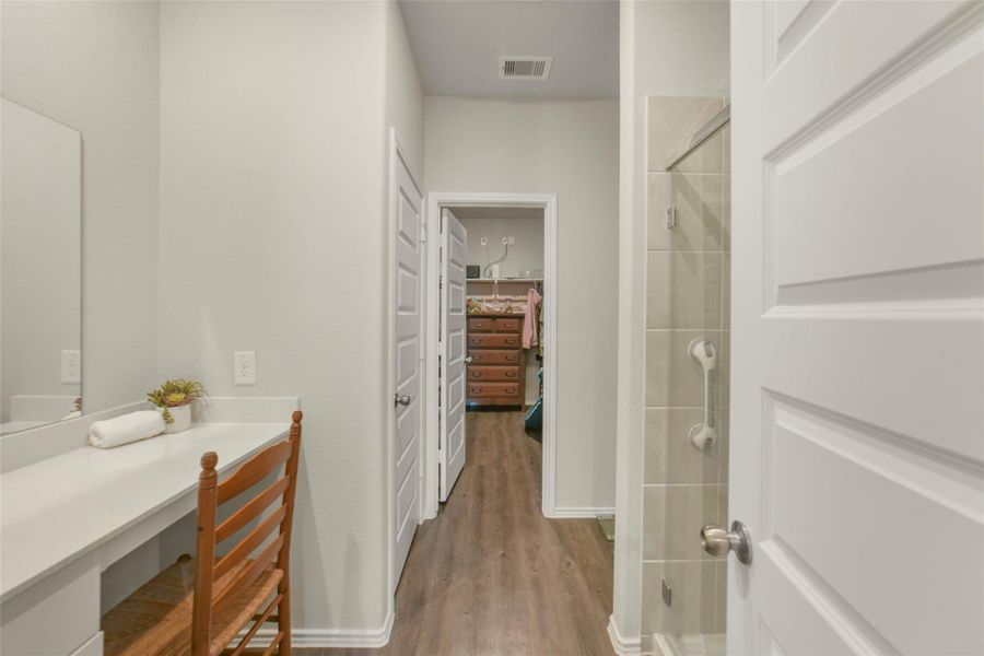 Bright bathroom with a modern design, featuring a spacious vanity and a tiled shower. The hallway leads to a walk-in closet with ample storage space. Bright bathroom with a modern design, featuring a spacious vanity and a tiled shower. The hallway leads to a walk-in closet with ample storage space.