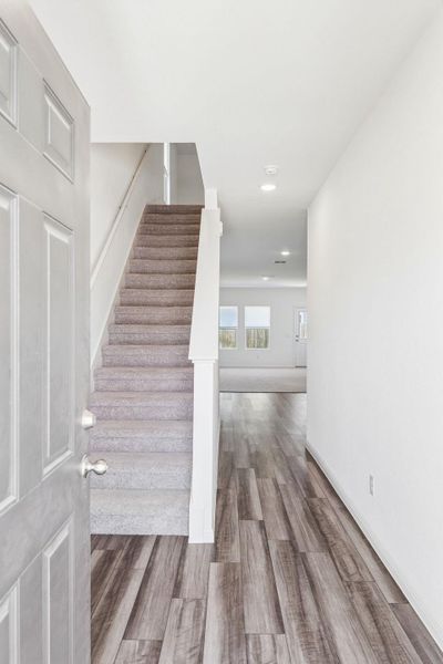 Stairway featuring wood finished floors and recessed lighting