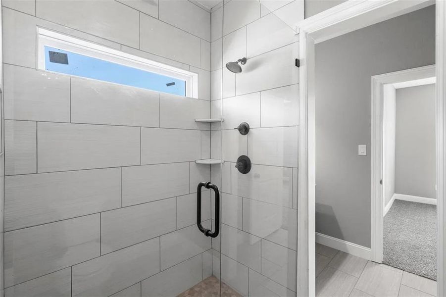 Bathroom featuring a shower stall and baseboards