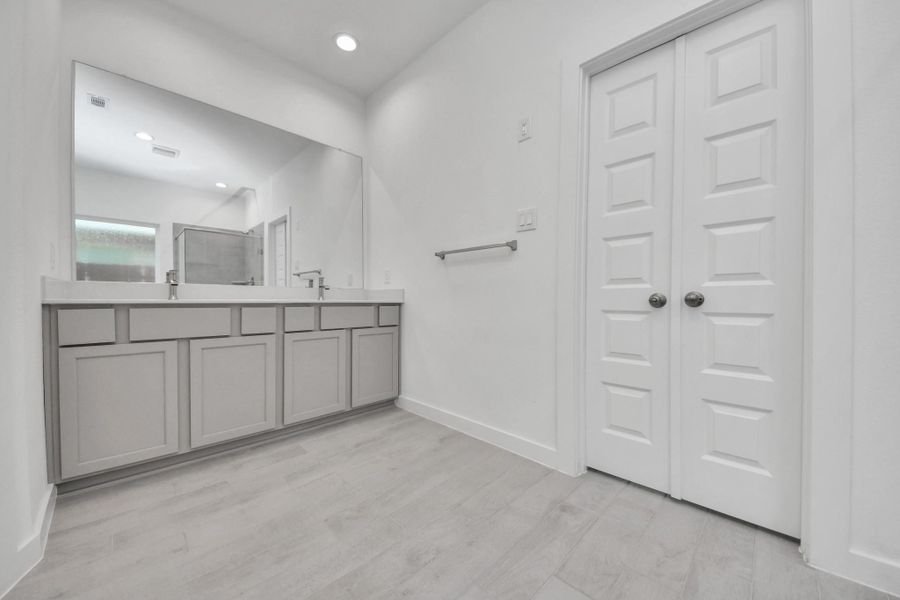 Elevate your daily routine at the elegant vanity, now equipped with double sinks, light countertops, modern hardware, and beautiful recessed lights. Sample photo of completed home with similar floor plan. Actual colors and selections may vary.