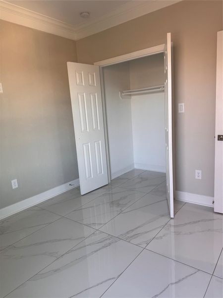 Bright room with elegant tile flooring and a spacious closet, perfect for storage. Bright room with elegant tile flooring and a spacious closet, perfect for storage.