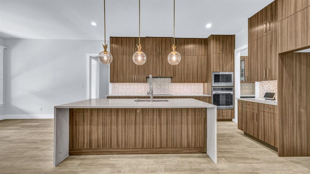 Kitchen with pendant lighting, a center island with sink, appliances with stainless steel finishes, and light hardwood / wood-style floors