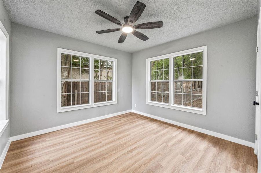 Unfurnished room featuring light wood-type flooring, a textured ceiling, and a ceiling fan Unfurnished room featuring light wood-type flooring, a textured ceiling, and a ceiling fan