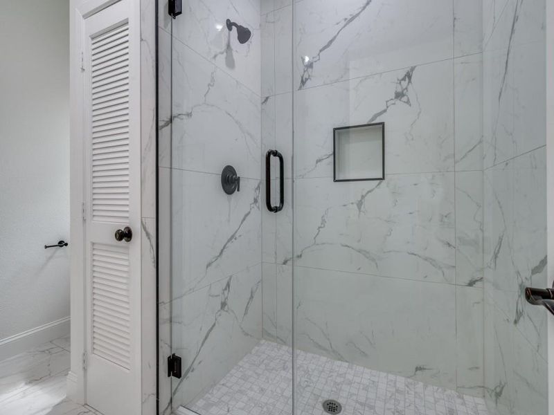 Bathroom with a marble finish shower, marble look tile flooring, and baseboards