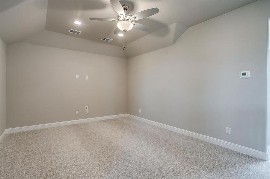 Empty room with ceiling fan, carpet flooring, and vaulted ceiling