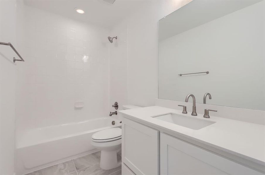 Full bathroom with tiled shower / bath combo, vanity, and toilet