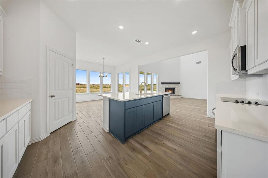 Kitchen with white cabinets, light wood finished floors, backsplash, a center island with sink, and recessed lighting Kitchen with white cabinets, light wood finished floors, backsplash, a center island with sink, and recessed lighting