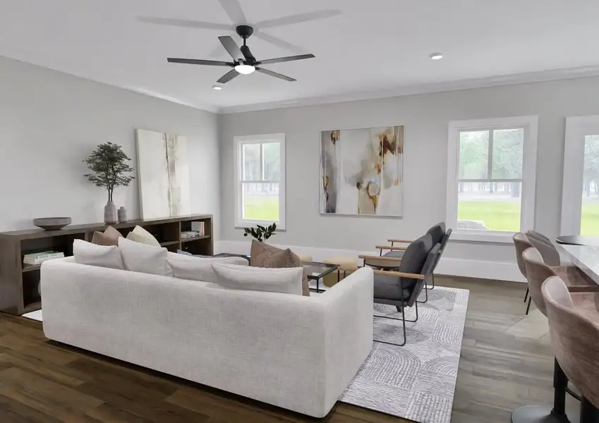 A modern living room featuring a ceiling fan, with an open view into a stylish kitchen area.