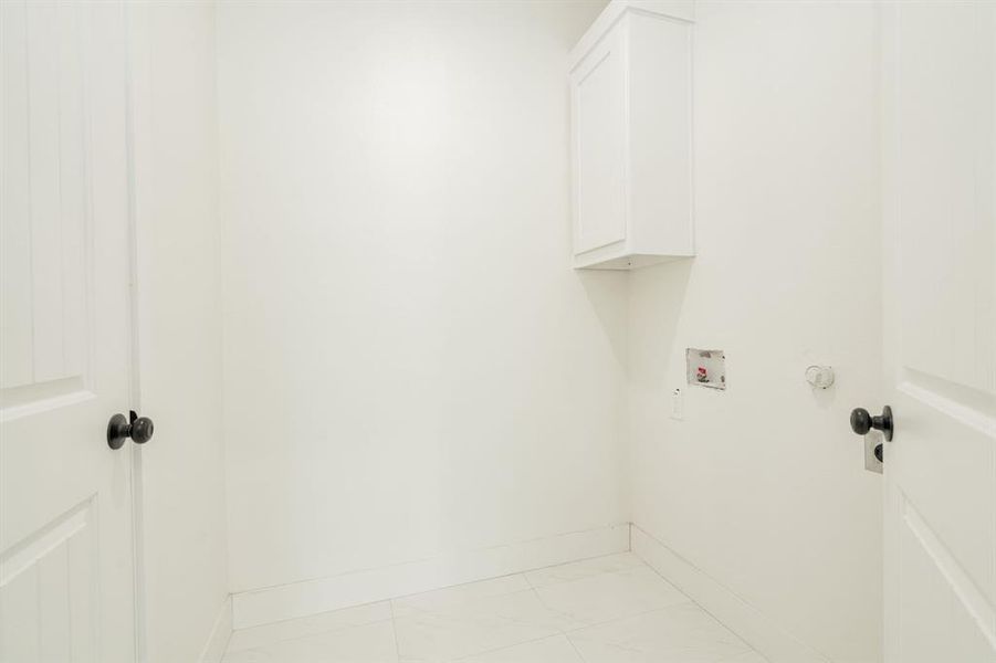 Washroom featuring hookup for a washing machine, cabinets, and light tile patterned floors