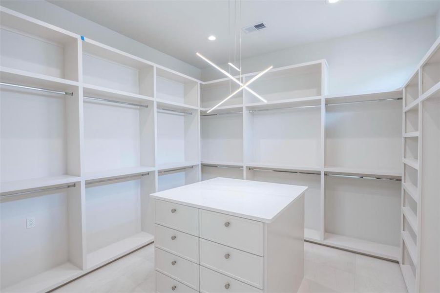 Walk in closet with an inviting chandelier and light tile floors Walk in closet with an inviting chandelier and light tile floors