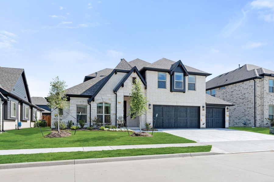 Two-story brick home with dark wood two-car garage, arched windows, and manicured front lawn Two-story brick home with dark wood two-car garage, arched windows, and manicured front lawn
