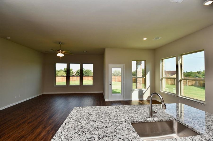 Kitchen with plenty of natural light, dark wood-style flooring, light stone counters, recessed lighting, and open floor plan