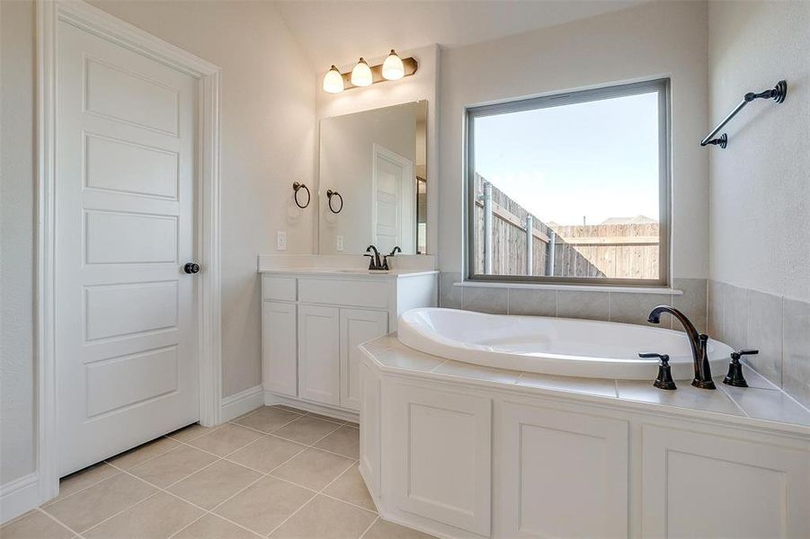 Bathroom featuring tile patterned floors, vanity, and a tub