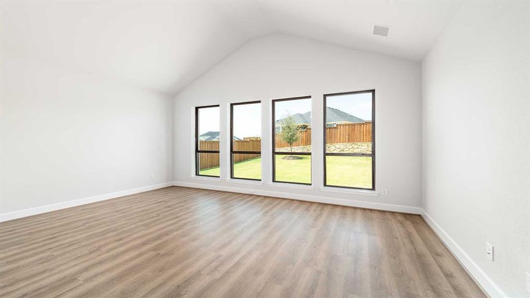 Empty room with high vaulted ceiling and light hardwood / wood-style flooring