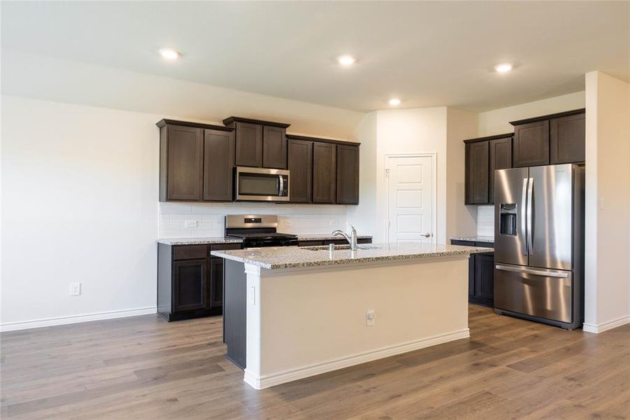 Kitchen featuring stainless steel appliances, light stone countertops, dark brown cabinets, dark wood-type flooring, and recessed lighting Kitchen featuring stainless steel appliances, light stone countertops, dark brown cabinets, dark wood-type flooring, and recessed lighting