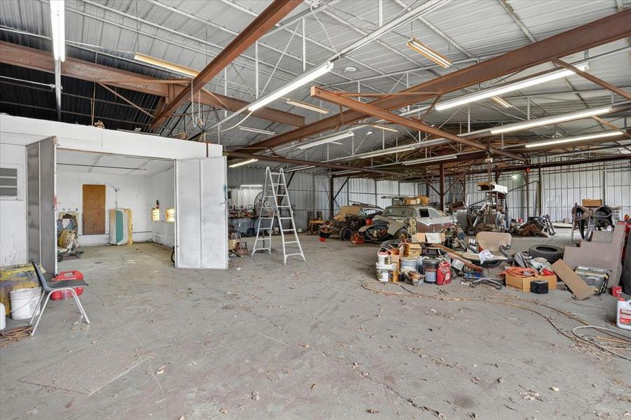 Garage space featuring a concrete floor, paint booth exposed metal beam structure, and high ceilings
