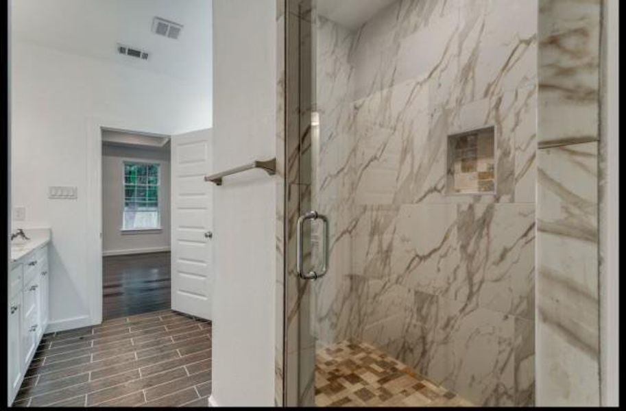 Bathroom with tile floors, a shower with shower door, and vanity