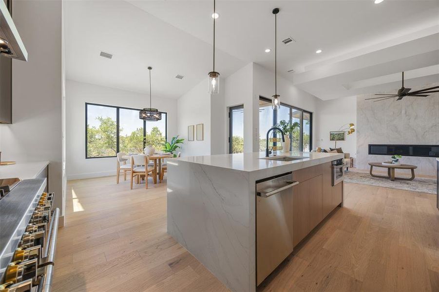 A luminous open-concept space features a well-appointed kitchen island, ample dining area, and a captivating fireplace lounge.