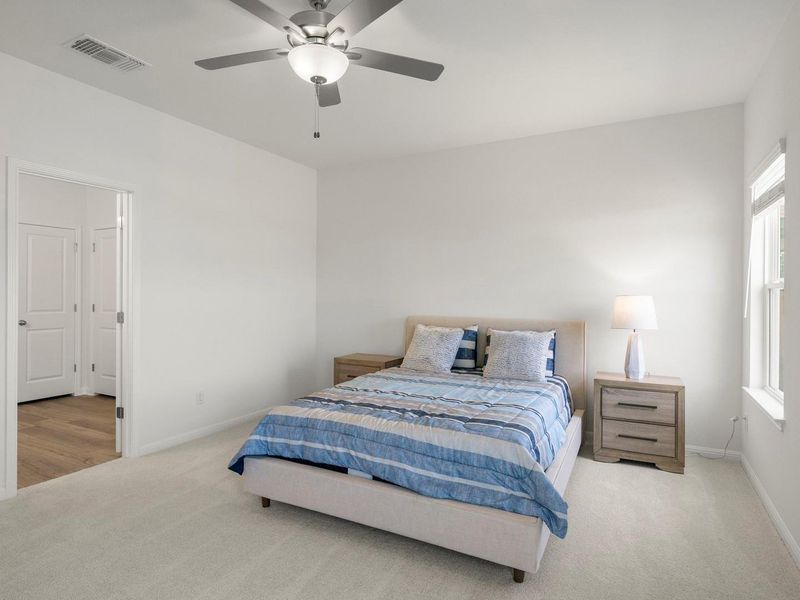 A well-lit bedroom provides comfortable repose with a ceiling fan for optimal airflow.