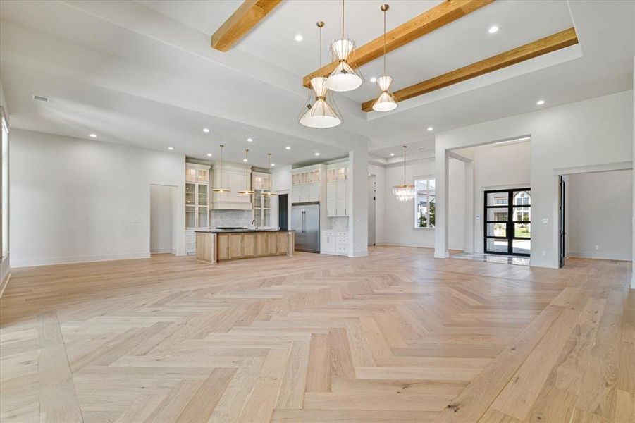 Unfurnished living room with a chandelier, beamed ceiling, recessed lighting, and a towering ceiling