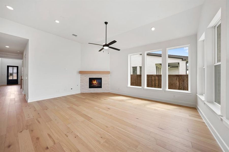 Unfurnished living room with light wood-type flooring, recessed lighting, plenty of natural light, and a fireplace Unfurnished living room with light wood-type flooring, recessed lighting, plenty of natural light, and a fireplace