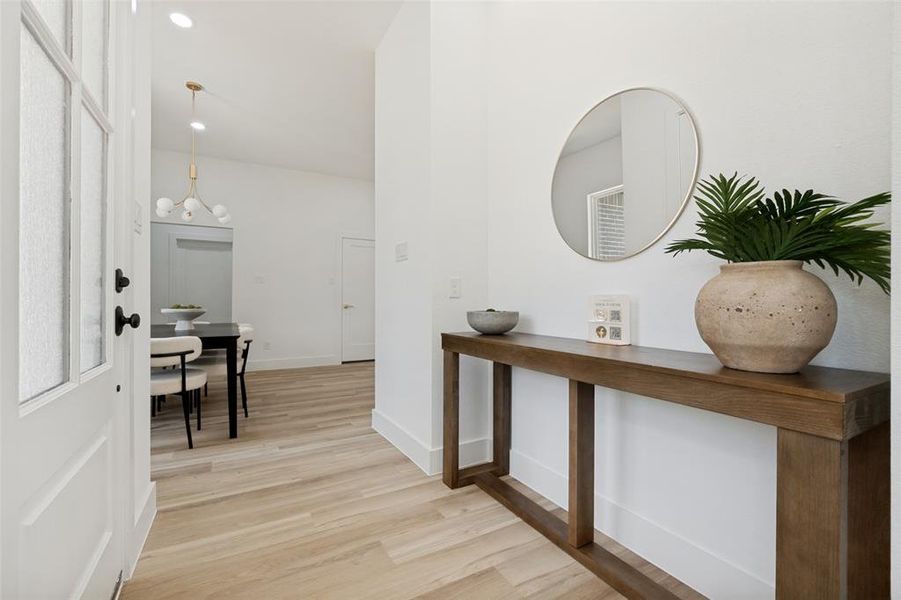 Entryway featuring a white paneled door with textured glass, matte black hardware, and wood-finish flooring Entryway featuring a white paneled door with textured glass, matte black hardware, and wood-finish flooring