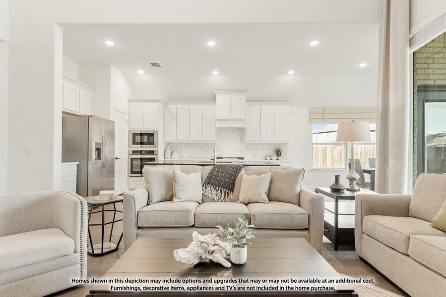Open-concept living room with neutral sofa and coffee table, open to kitchen with white cabinets and stainless appliances Open-concept living room with neutral sofa and coffee table, open to kitchen with white cabinets and stainless appliances
