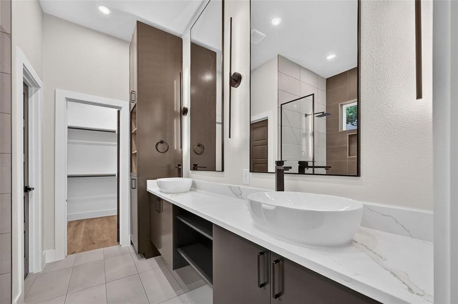 Double vanity with vessel sinks, quartz countertops, dark wood-finish cabinetry, and contemporary lighting Double vanity with vessel sinks, quartz countertops, dark wood-finish cabinetry, and contemporary lighting