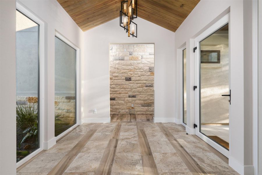 Corridor with wooden ceiling, a notable chandelier, and lofted ceiling