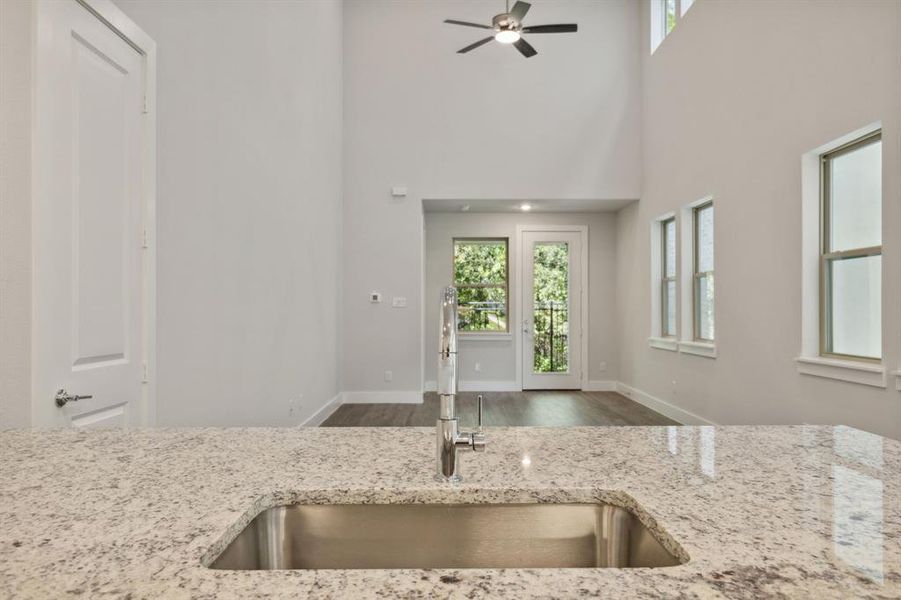 Open kitchen featuring wood finished floors, light stone counters, a sink, and baseboards