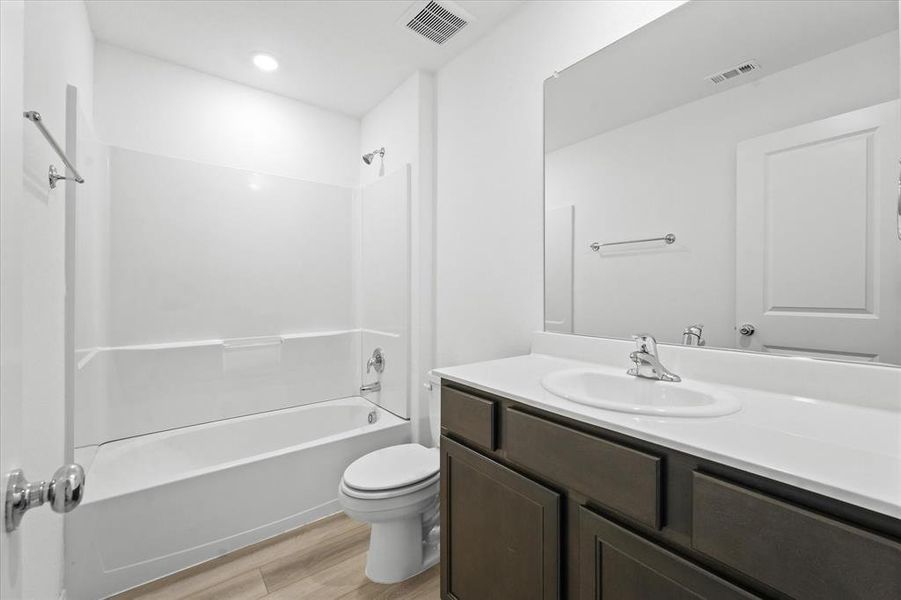 Full bathroom with vanity, wood-type flooring, toilet, and washtub / shower combination