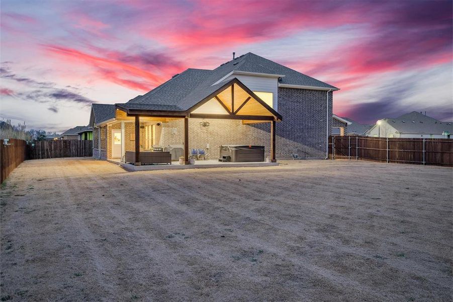 Rear view of property with a fenced backyard, a hot tub, brick siding, and a patio area