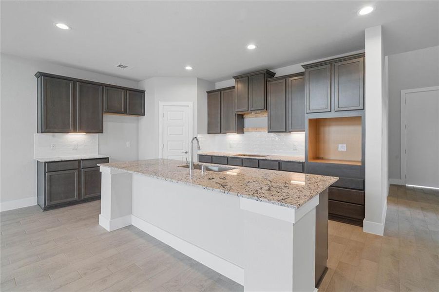 This kitchen is by far any chef’s dream! This spacious kitchen features high ceilings, stained wood cabinets, quartz countertops, SS appliances, modern tile backsplash, recessed lighting, quartz kitchen island with space for breakfast bar and extra storage, and a walk-in pantry all overlooking your huge family room.