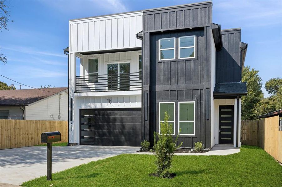View of front of property with board and batten siding, driveway, a garage, and a balcony