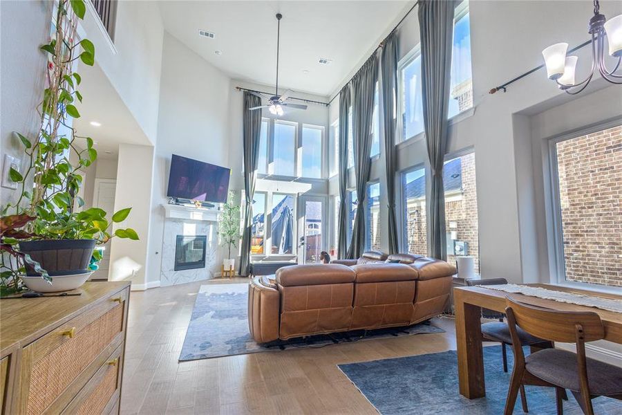 Living room featuring a high end fireplace, hardwood / wood-style floors, a high ceiling, ceiling fan, and a chandelier