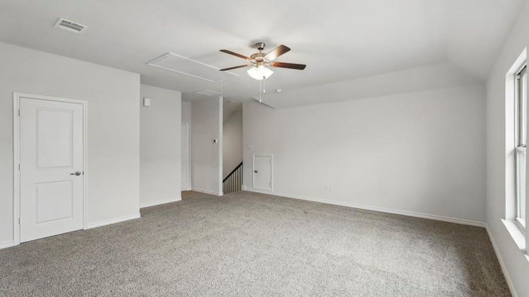 Spacious room featuring neutral carpeting, light-colored walls, and a ceiling fan with integrated lighting