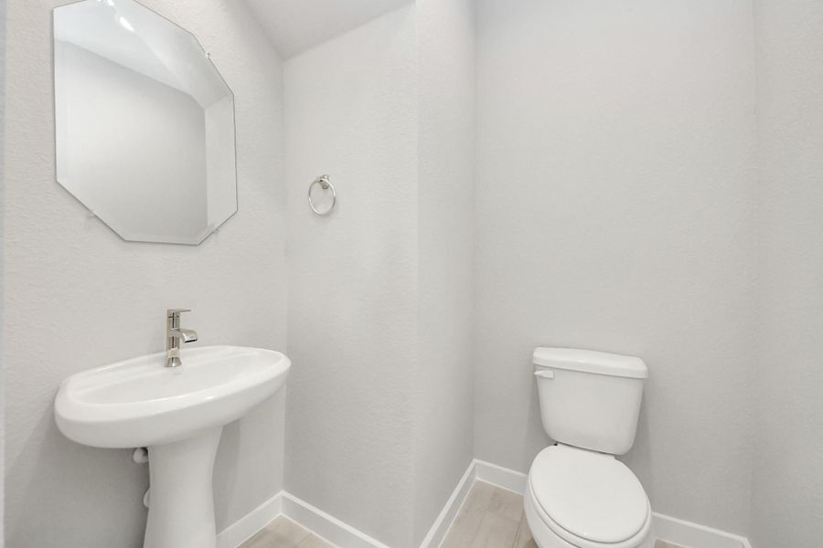 This half bathroom features a stylish pedestal sink, modern hardware, and bright recessed lighting, creating a sleek and inviting space.