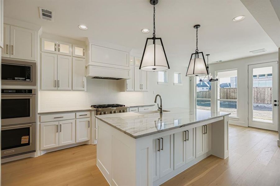 Kitchen with white cabinets, appliances with stainless steel finishes, light stone countertops, and recessed lighting Kitchen with white cabinets, appliances with stainless steel finishes, light stone countertops, and recessed lighting