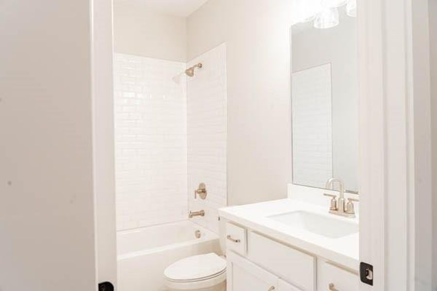 Full bathroom featuring tiled shower / bath, toilet, and oversized vanity Full bathroom featuring tiled shower / bath, toilet, and oversized vanity