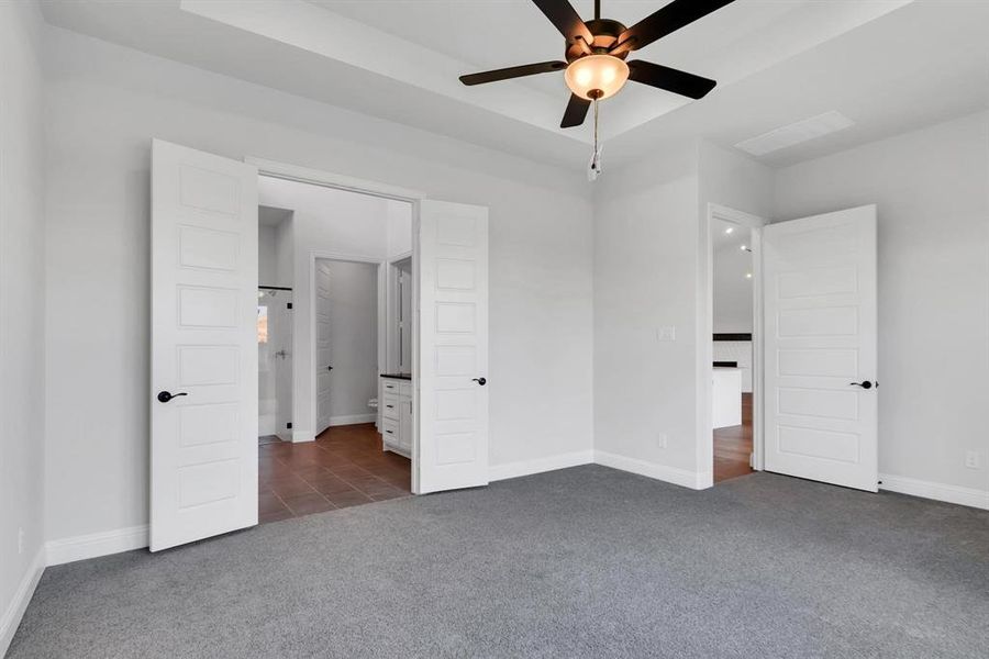 Unfurnished bedroom with dark colored carpet and ceiling fan