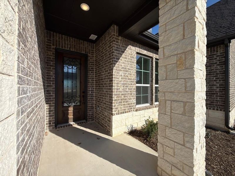 Entrance to property featuring brick siding and covered porch