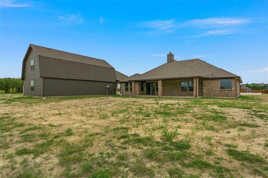 New construction home featuring brick exterior, covered patio, and a separate two-story structure with siding